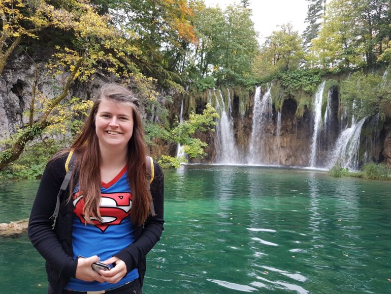 My girlfriend at a azure blue lake with waterfalls on the back of the lake