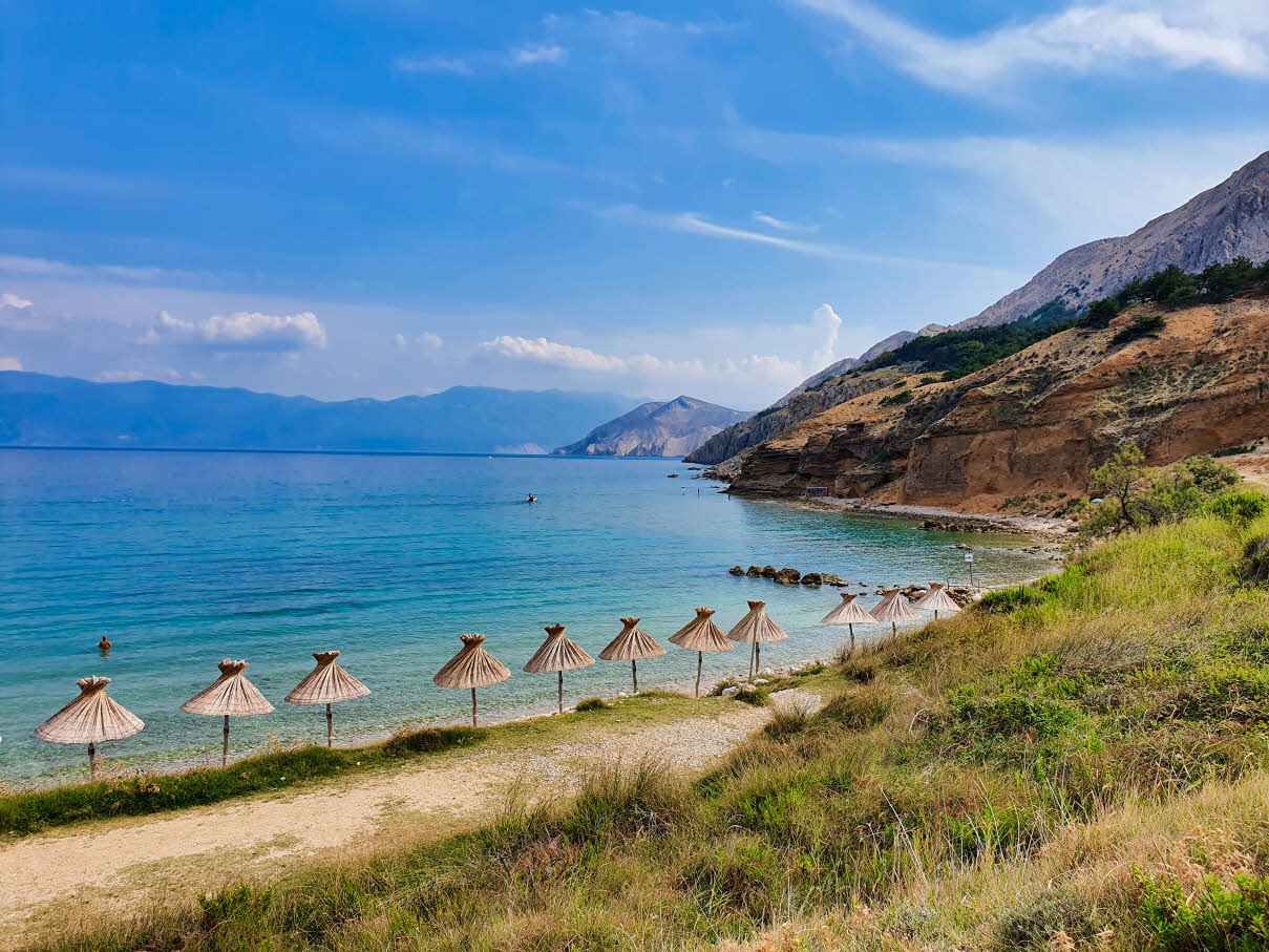 Umbrellas along the shore on Vela Plaža Baška beach